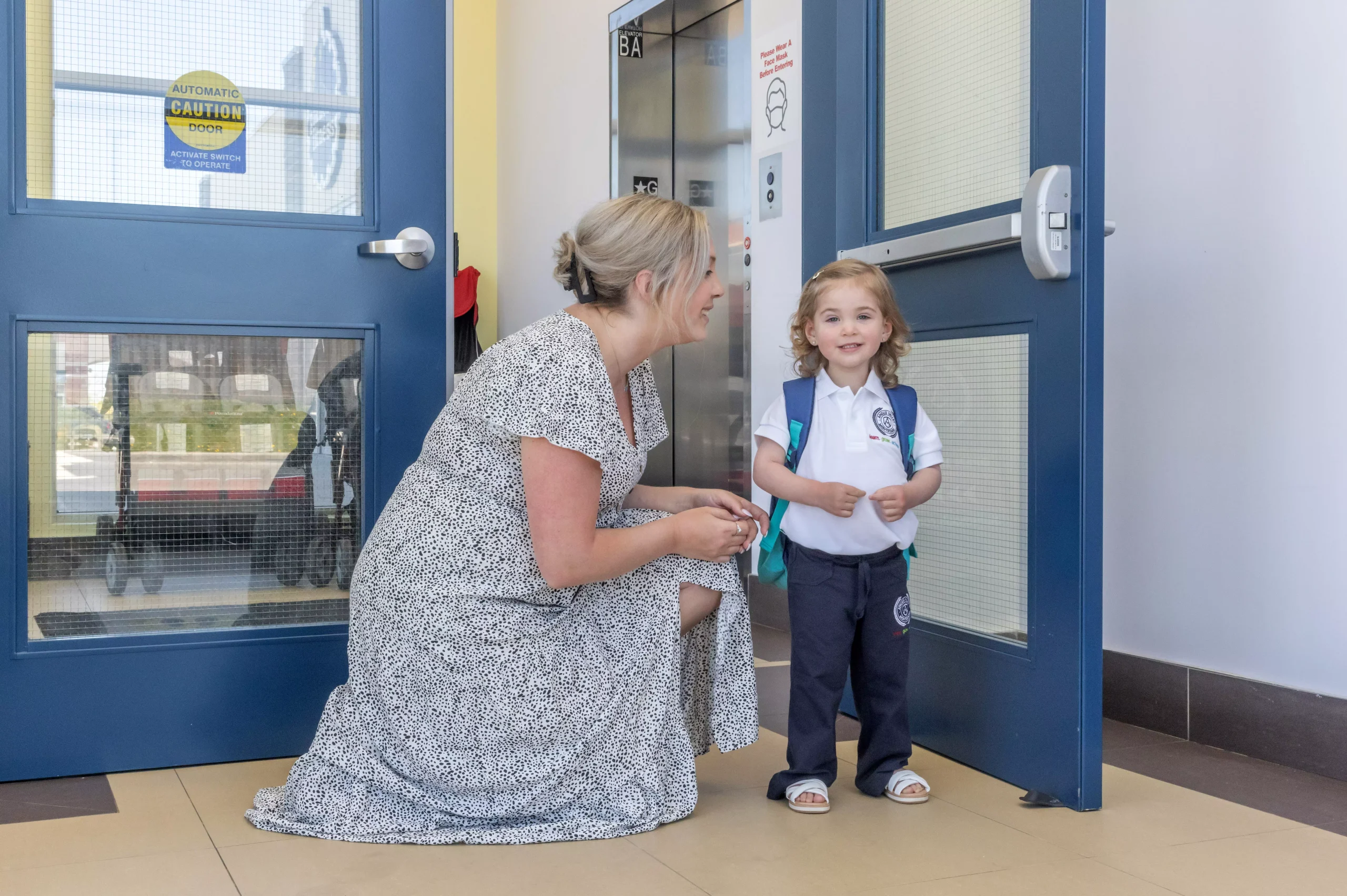 ALT "A mother says goodbye to her young daughter during drop-off time."